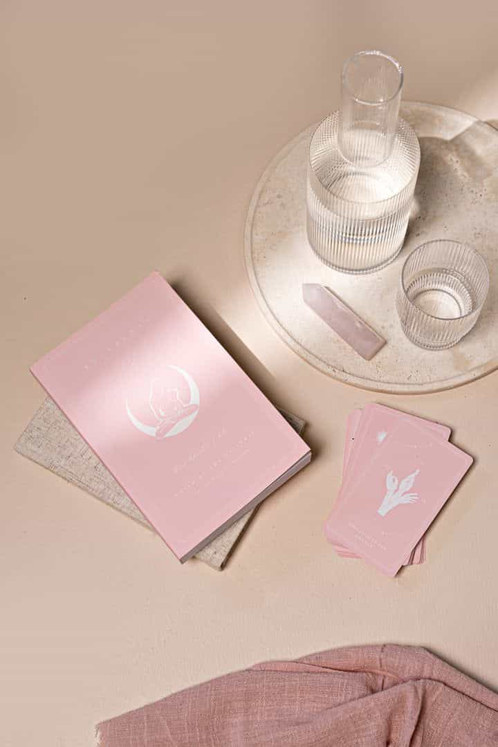 imagen de cartas de tarot, un cuarzo rosa y un vaso de agua, en estética rosa